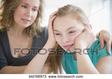 Stock Image - Caucasian mother comforting crying daughter. Fotosearch