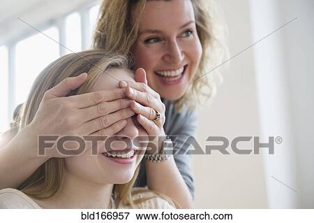 Stock Photo - Caucasian mother covering eyes of daughter. Fotosearch