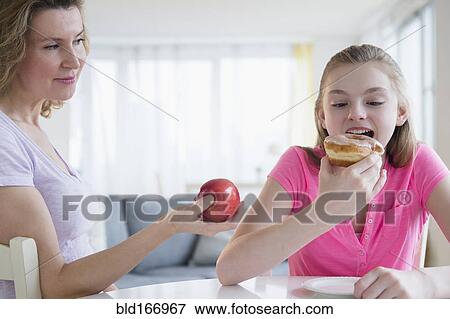 Caucasian mother offering daughter healthy food View Large Photo Image Stock Photo - Caucasian mother offering daughter healthy food. Fotosearch