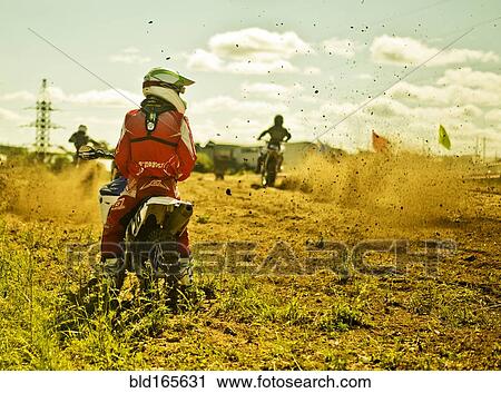 Stock Image - Caucasian motocross biker waiting on race course. Fotosearch