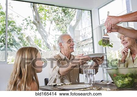 Picture - Caucasian multi-generation family eating at table. Fotosearch