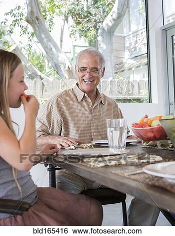 Stock Photograph - Caucasian multi-generation family eating at table. Fotosearch