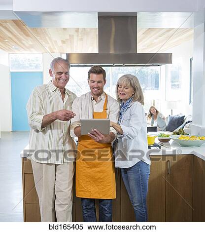 Stock Photography - Caucasian parents and son using digital tablet in kitchen. Fotosearch