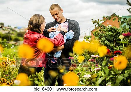 Caucasian parents holding baby near flowers View Large Photo Image Stock Image - Caucasian parents holding baby near flowers. Fotosearch