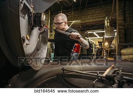Stock Photography - Caucasian roaster working on coffee in warehouse. Fotosearch