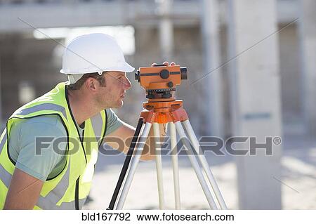 Stock Image - Caucasian surveyor examining construction site. Fotosearch