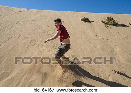 Caucasian teenage boy sliding on sand dune View Large Photo Image Stock Photo - Caucasian teenage boy sliding on sand dune. Fotosearch