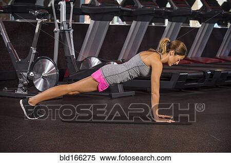 Stock Photography - Caucasian woman doing push-ups in gym. Fotosearch