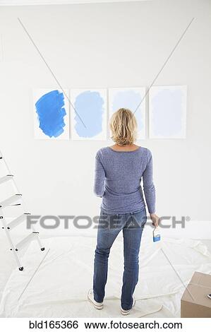 Stock Photograph - Caucasian woman examining paint samples in new home. Fotosearch
