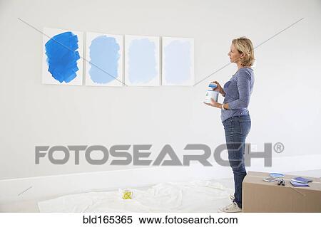 Stock Photography - Caucasian woman examining paint samples in new home. Fotosearch