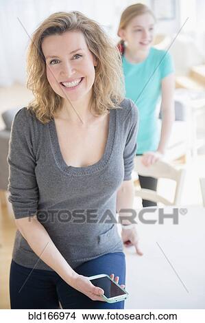 Caucasian woman holding cell phone in dining room View Large Photo Image Picture - Caucasian woman holding cell phone in dining room. Fotosearch