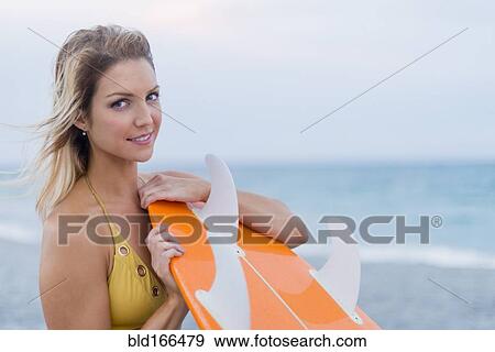 Caucasian woman holding surfboard on beach View Large Photo Image Stock Photo - Caucasian woman holding surfboard on beach. Fotosearch