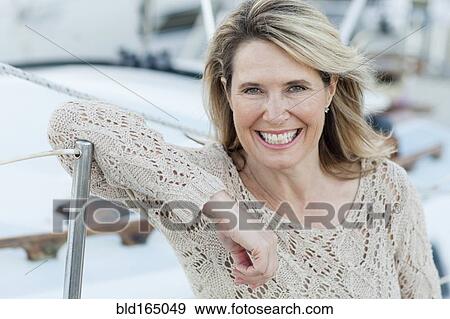 Stock Photo - Caucasian woman leaning on boat in harbor. Fotosearch