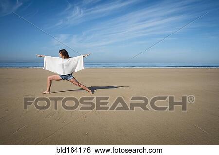 Stock Photograph - Caucasian woman practicing yoga on beach. Fotosearch