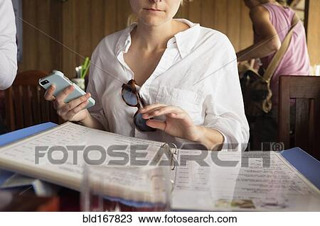 Stock Image - Caucasian woman reading menu in restaurant. Fotosearch