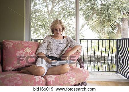 Stock Photo - Caucasian woman reading on sofa. Fotosearch