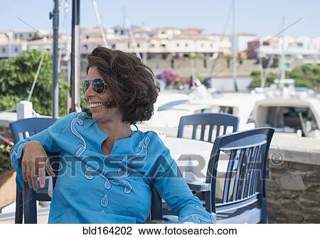 Stock Image - Caucasian woman sitting at outdoor cafe. Fotosearch