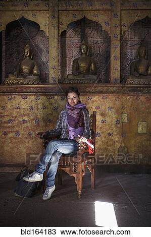 Stock Image - Caucasian woman sitting in chair in temple. Fotosearch