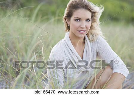 Stock Image - Caucasian woman sitting on beach. Fotosearch