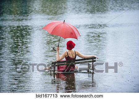 Caucasian woman sitting on bench in flood View Large Photo Image Stock Image - Caucasian woman sitting on bench in flood. Fotosearch