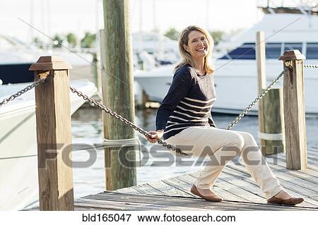 Caucasian woman sitting on dock in harbor View Large Photo Image Stock Photo - Caucasian woman sitting on dock in harbor. Fotosearch