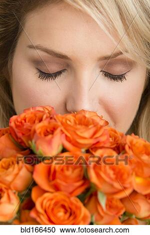 Stock Image - Caucasian woman smelling bouquet of flowers. Fotosearch