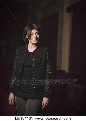 Stock Image - Caucasian woman standing in movie theater. Fotosearch