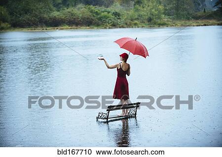 Stock Image - Caucasian woman standing on bench in flood. Fotosearch