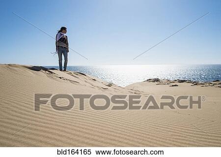Caucasian woman standing on sand dune near ocean View Large Photo Image Stock Photography - Caucasian woman standing on sand dune near ocean. Fotosearch