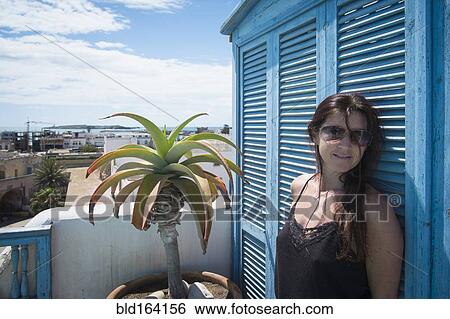 Stock Photograph - Caucasian woman standing on urban balcony. Fotosearch
