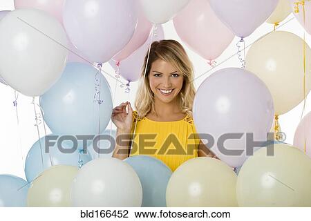 Stock Image - Caucasian woman standing with balloons. Fotosearch