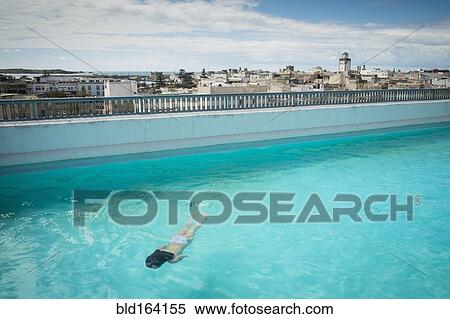 Stock Photography - Caucasian woman swimming in urban rooftop pool. Fotosearch