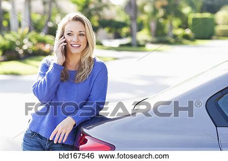 Stock Photograph - Caucasian woman talking on cell phone at car. Fotosearch