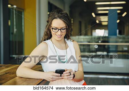 Picture - Caucasian woman using cell phone in cafe. Fotosearch
