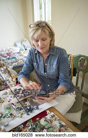 Stock Photo - Caucasian woman using cell phone in craft room. Fotosearch