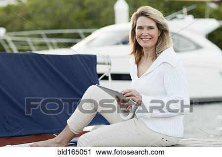 Stock Image - Caucasian woman using digital tablet on boat deck. Fotosearch
