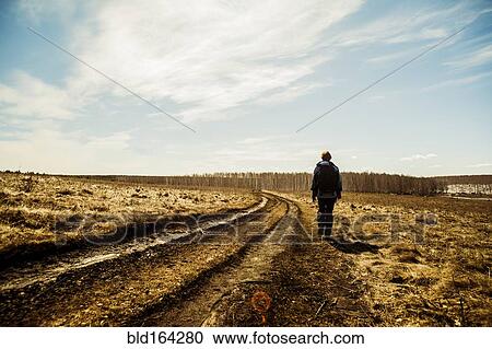 Stock Image - Caucasian woman walking in rural field. Fotosearch