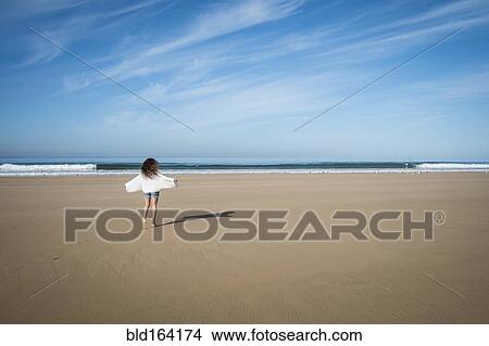 Picture - Caucasian woman walking on beach under blue sky. Fotosearch