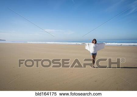 Stock Photography - Caucasian woman walking on beach under blue sky. Fotosearch