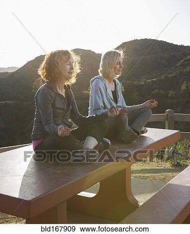 Stock Photo - Caucasian women meditating on hilltop. Fotosearch