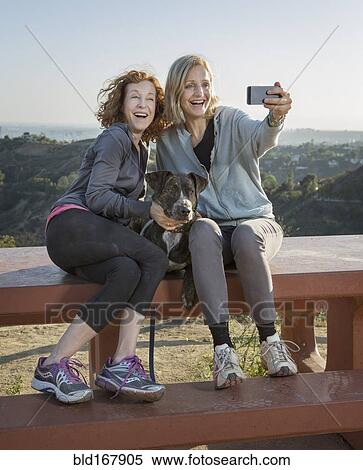 Stock Photography - Caucasian women taking selfie on hilltop. Fotosearch