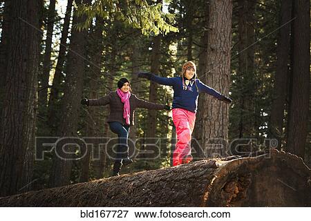 Children balancing on log in forest View Large Photo Image Stock Photo - Children balancing on log in forest. Fotosearch