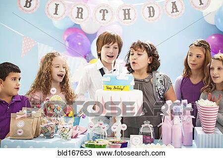 Children blowing out candles on birthday cake at party View Large Photo Image Stock Image - Children blowing out candles on birthday cake at party. Fotosearch