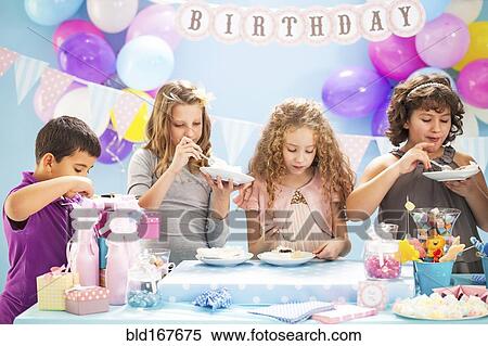 Stock Photography - Children eating cake at birthday party. Fotosearch