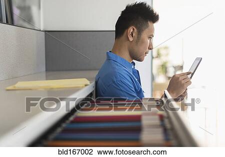 Stock Image - Chinese businessman using digital tablet in office. Fotosearch