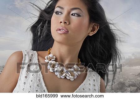 Stock Photo - Close up of Asian woman standing on rocky coast. Fotosearch