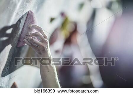 Stock Photo - Close up of athlete climbing rock wall in gym. Fotosearch