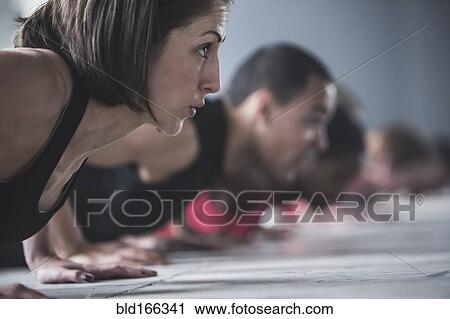 Stock Image - Close up of athletes doing push-ups on floor. Fotosearch