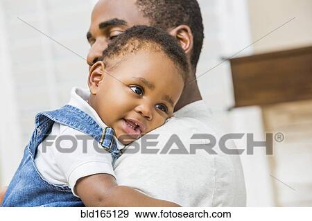 Close up of Black father holding baby son View Large Photo Image Stock Photo - Close up of Black father holding baby son. Fotosearch