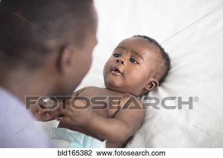 Close up of Black father playing with baby on bed View Large Photo Image Stock Image - Close up of Black father playing with baby on bed. Fotosearch